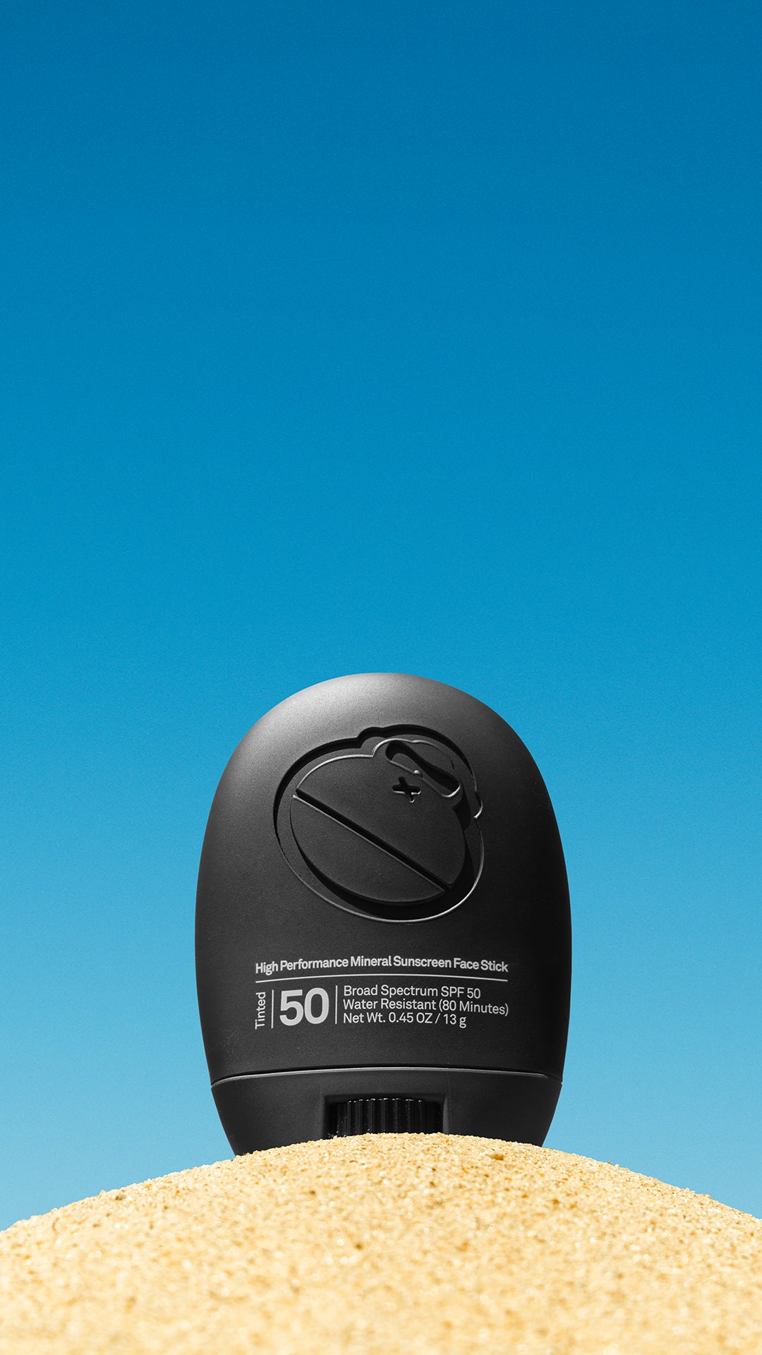 Signature Face Stick on top of a sand hill with a blue background.