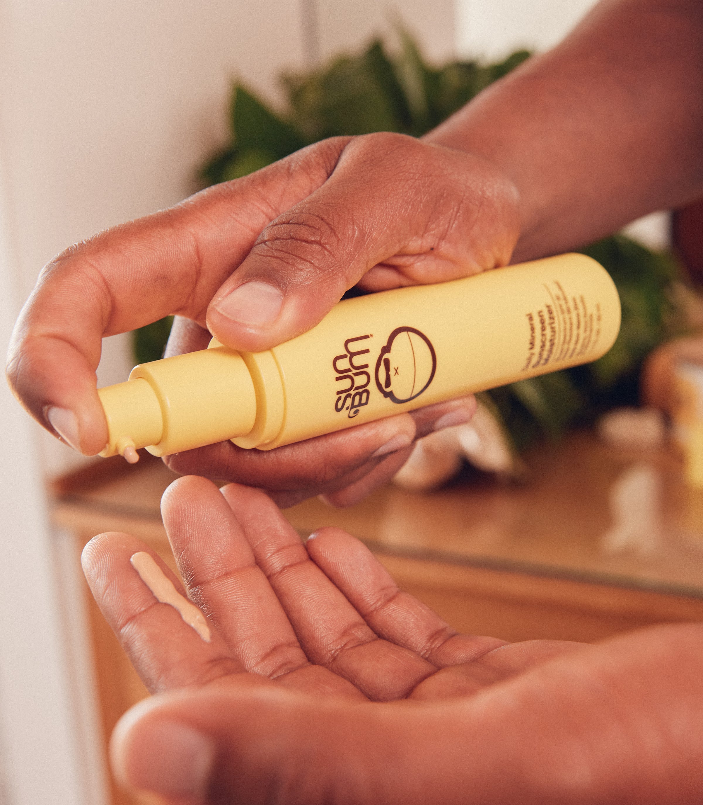 Close-up of hands dispensing face lotion from a yellow bottle, showcasing the SB Everyday Skin Care Collection – Sun Bum.