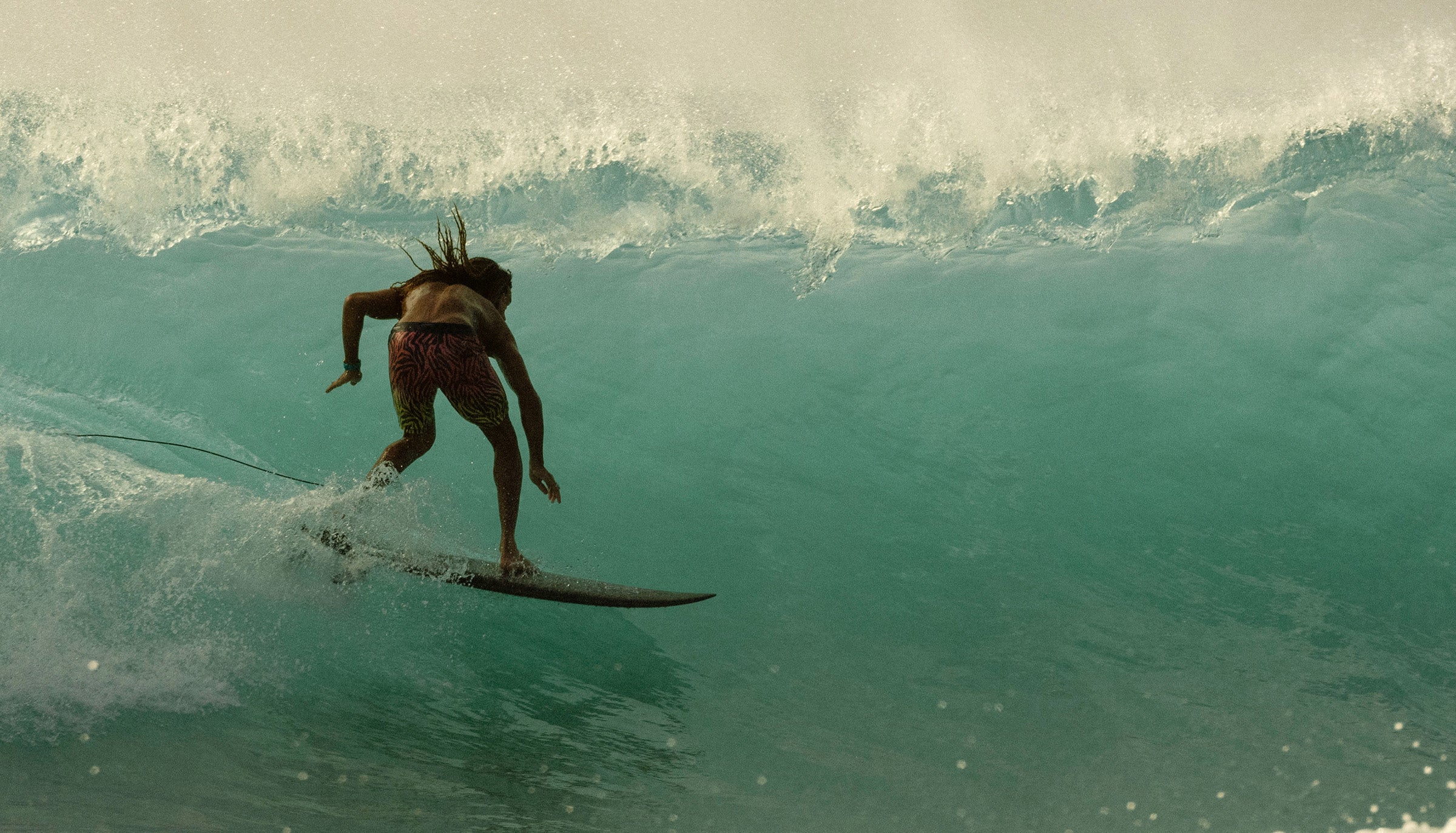 Surfer riding inside a powerful turquoise barrel wave, capturing bold adventure – Signature Collection - Sun Bum.