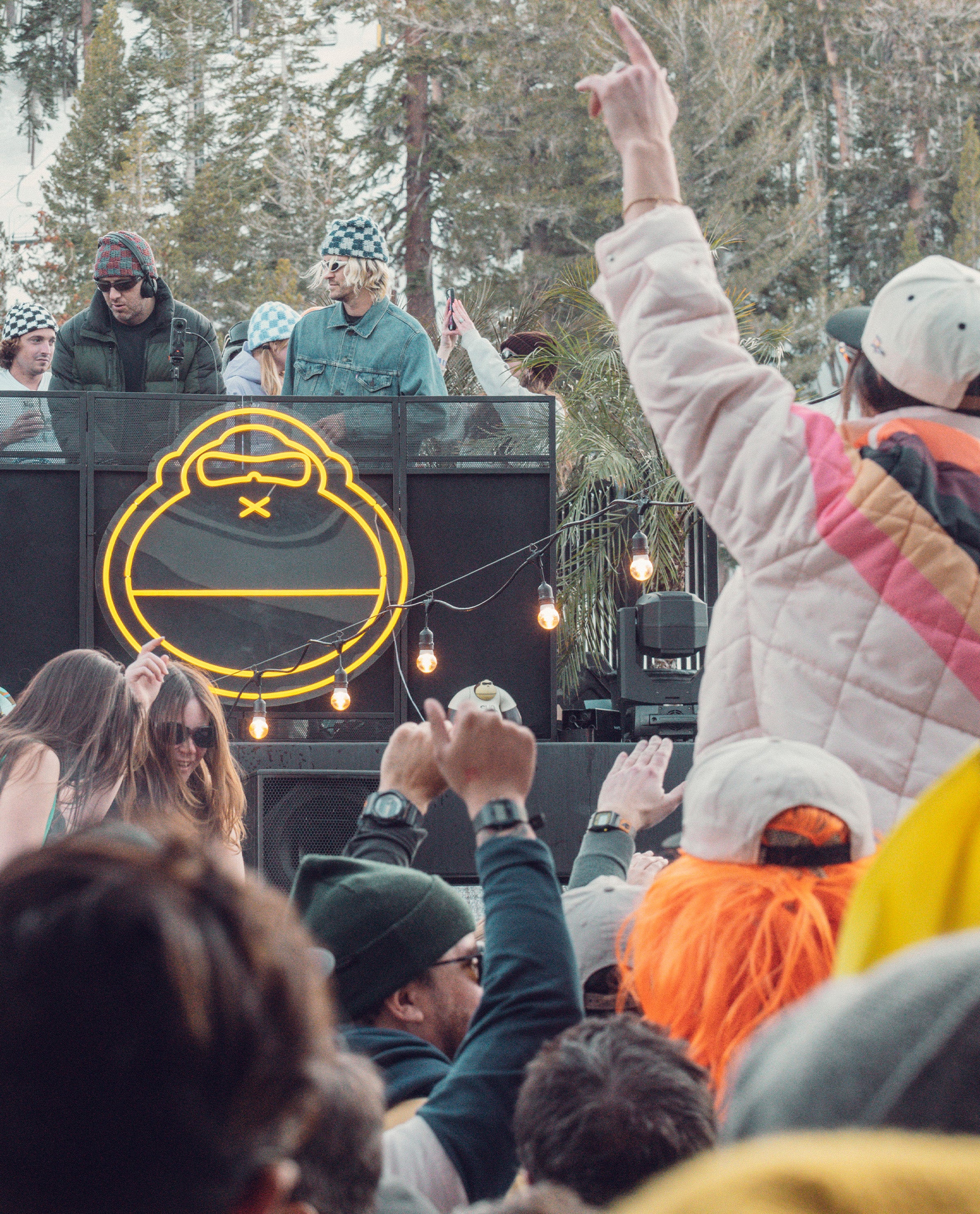 Crowd enjoying outdoor DJ set with neon Sunny logo and winter vibes – Ask The Bum Community - Sun Bum