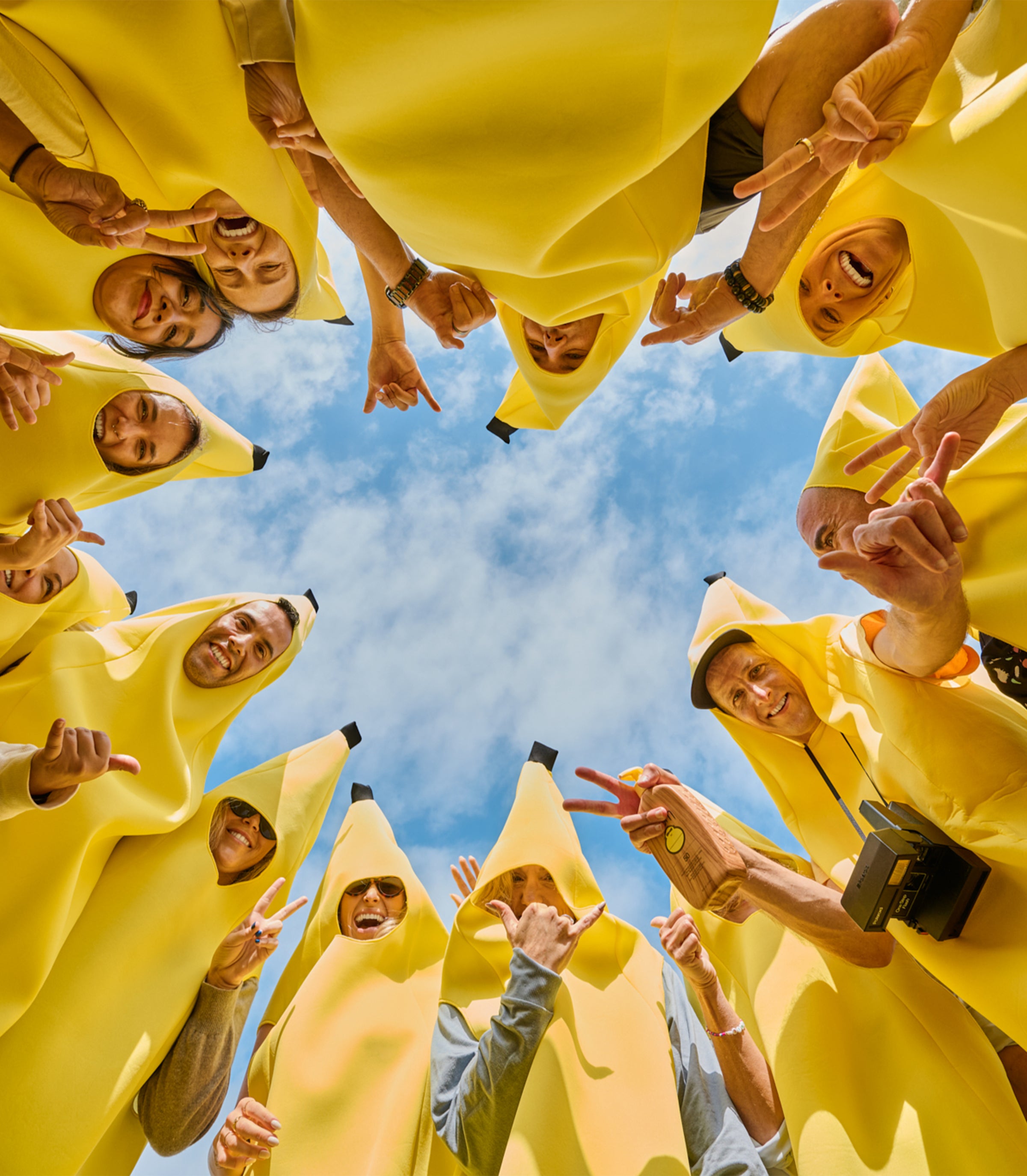 Group of friends in banana costumes throwing peace signs and holding sunscreen from the SB Original Sunscreen Collection – Sun Bum.