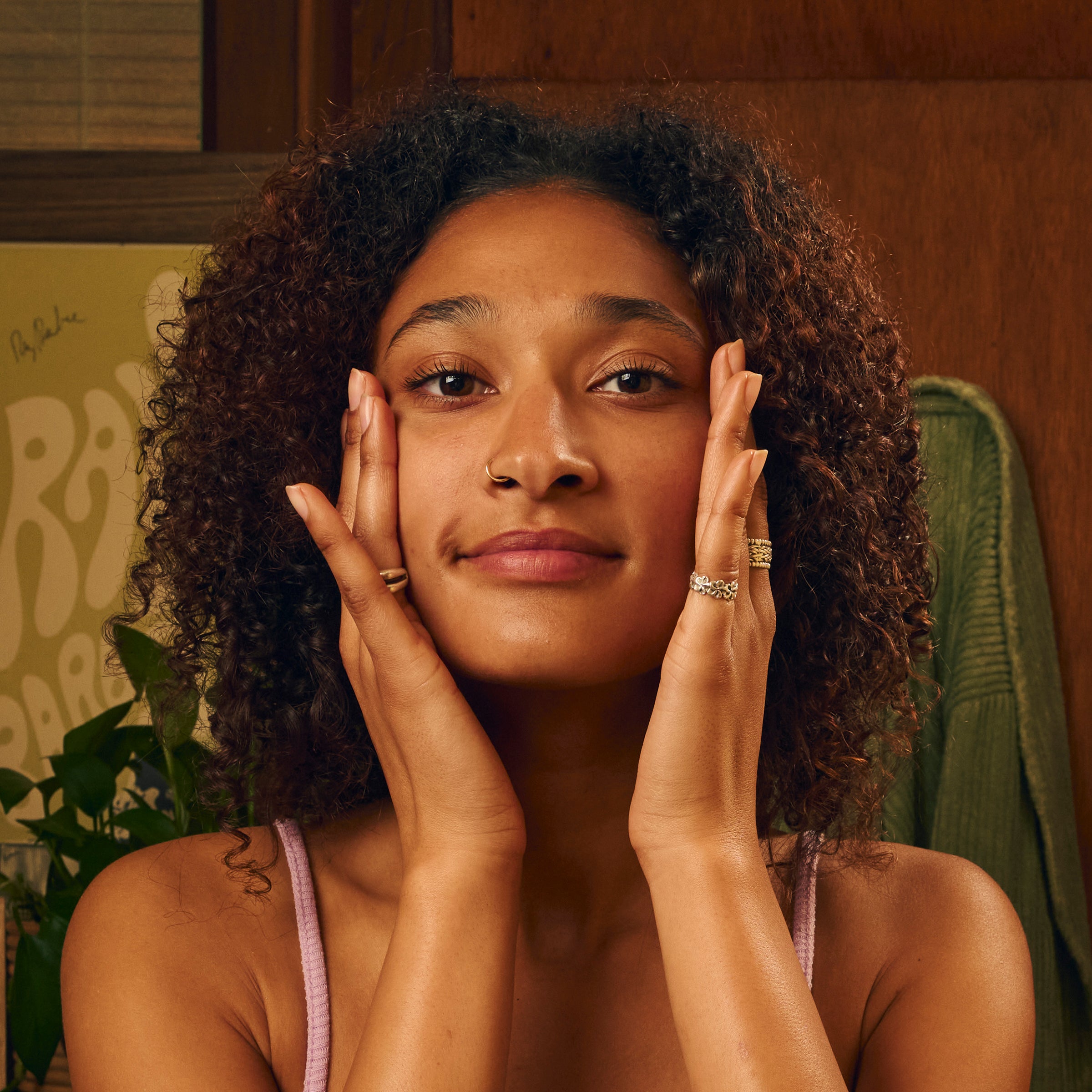 Woman applying facial sunscreen with a natural glow in cozy indoor setting – Daily Collection - Sun Bum.