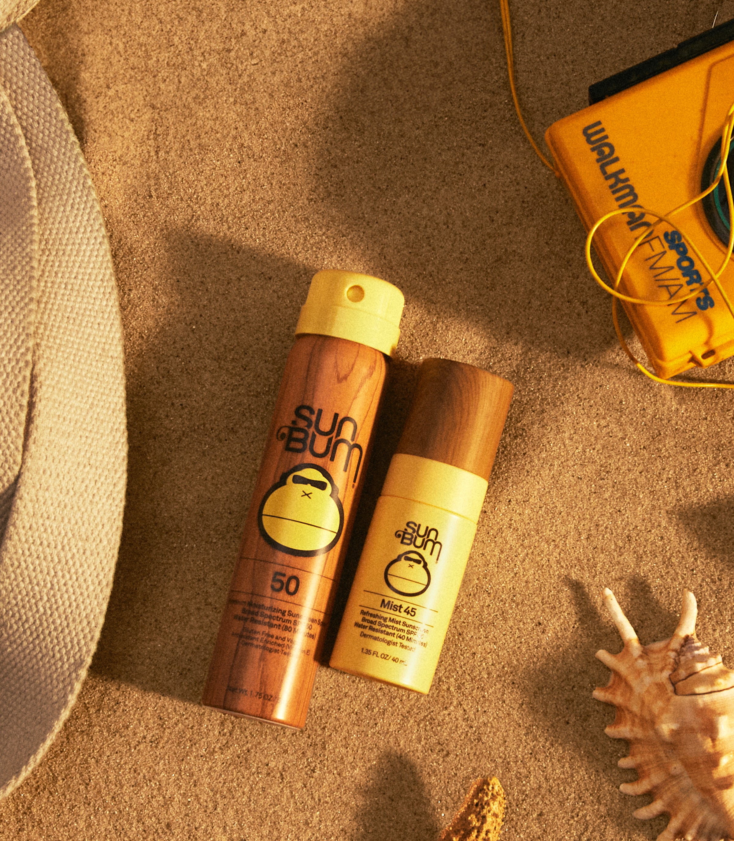Flat lay of Sun Bum travel size sunscreen and face mist on beach sand with retro gear – Travel Size Sunscreen Collection - Sun Bum.