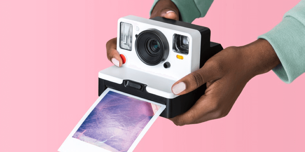 Photo of hands holding a polaroid camera with the blog post title and Tailwind logo on a pink background. 